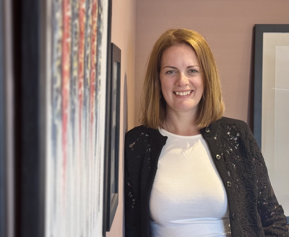 Heather Stewart smiling, leaning against a wall.