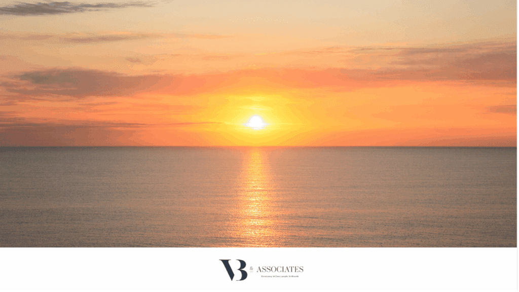 orange sunset over calm ocean water. the sun is reflecting in the water like an orange beam.